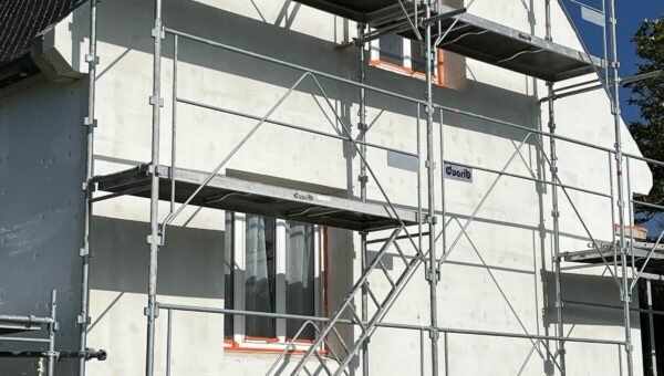Maison sous échafaudage pendant un chantier d'isolation par l'extérieur