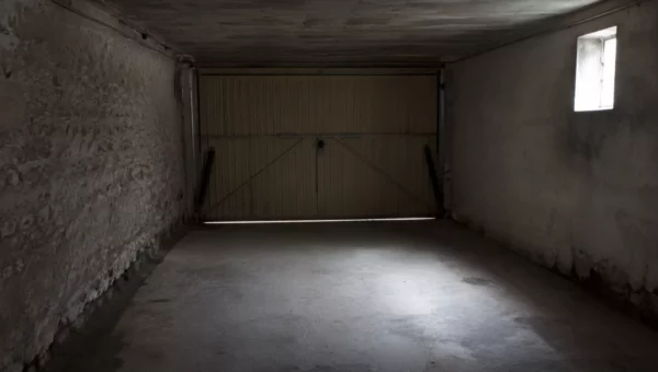 Intérieur de garage fermé, mur en pierre et bas de mur plus sombre le long du sol en béton