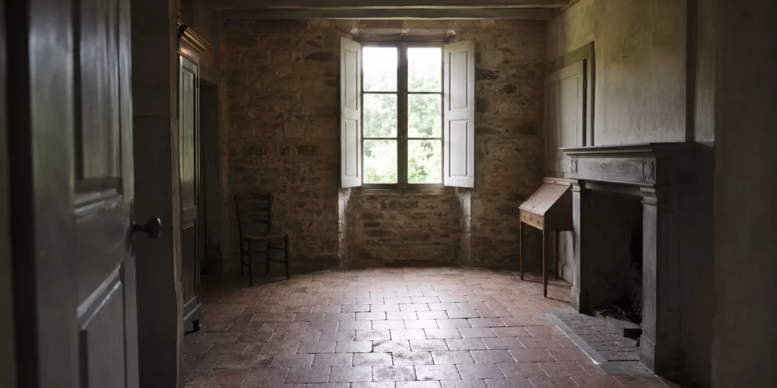 Intérieur confiné d'une maison ancienne aux murs de pierre et au sol en tomettes