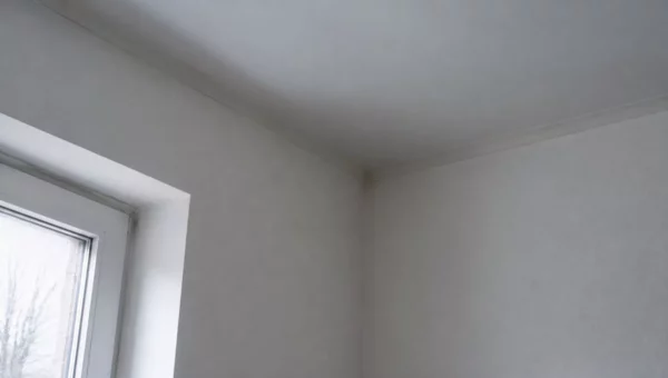 Jonction entre un mur et un plafond dans une pièce chauffée, près d'une fenêtre en hiver